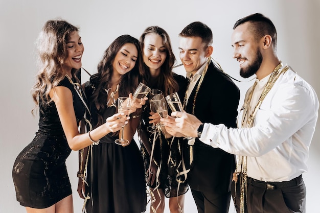 Friends in stylish elegant clothes smile together holding glasses of champagne in hands