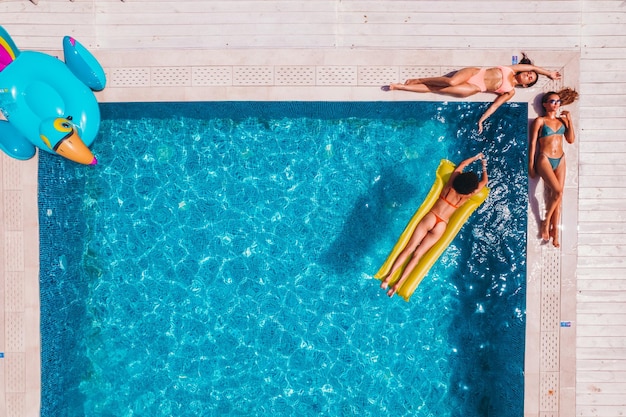 Friends in swimsuit who tan in the sunbed in a swimming pool