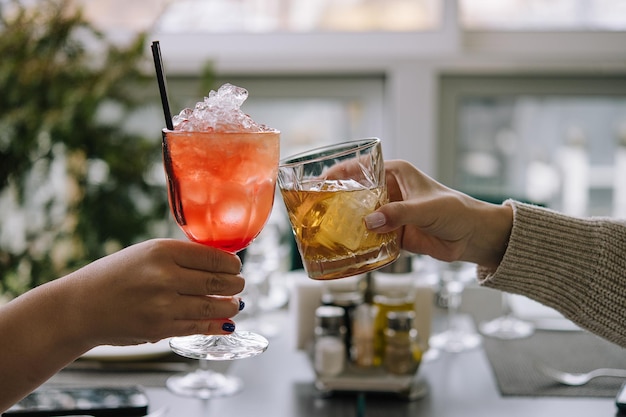 Friends toasting with glasses of whiskey and strawberry cocktail