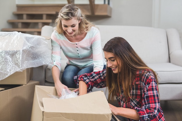 Friends unpacking carton boxes