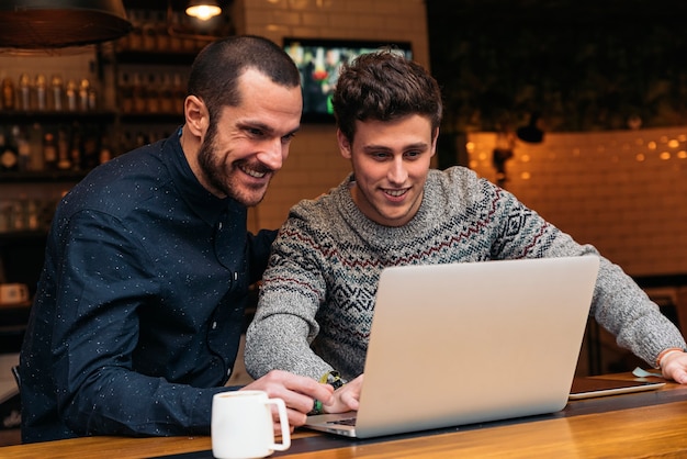 Friends using mobile and laptop in a coffee shop.