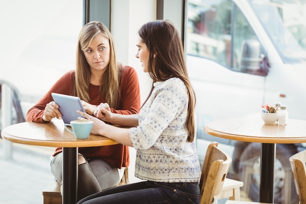 Friends using tablet and having coffee in a coffee shop