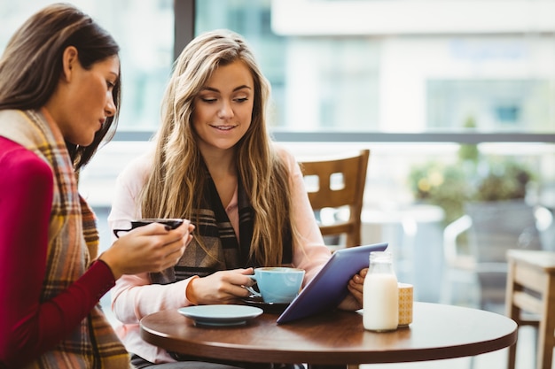 Friends using tablet together in cafe