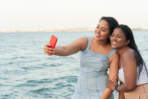 Friends using their cell phones in the city They are taking a selfie with their smartphone by the sea