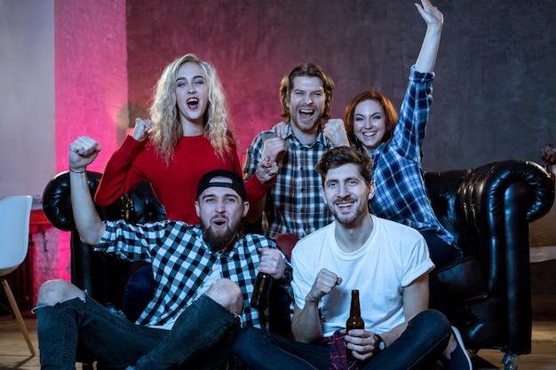 Friends watching a football match and drinking beer.