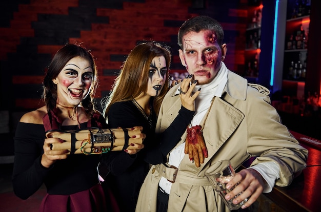 Friends with bomb in hands is on the thematic halloween party in scary makeup and costumes.