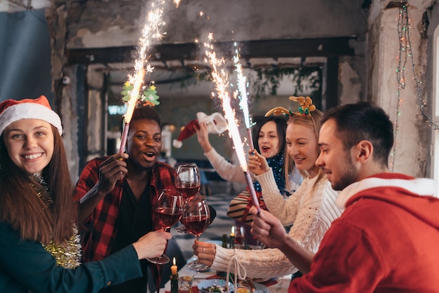 Friends with sparklers in hands. Group of friends celebrating Christmas eve together.