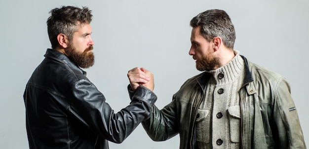 Photo friendship of brutal guys leadership concept true friendship of mature friends male friendship brutal bearded men wear leather jackets shaking hands real men and brotherhood strong handshake