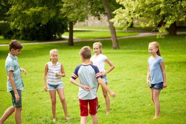 friendship, childhood, leisure and people concept - group of happy kids or friends playing game in summer park