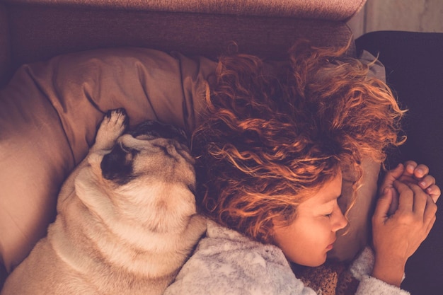 Friendship concepts for 40s woman sleeping with her best firends pug dog at home Both on the pillow and brown warm tones Dreaming together Love and friendship image mood