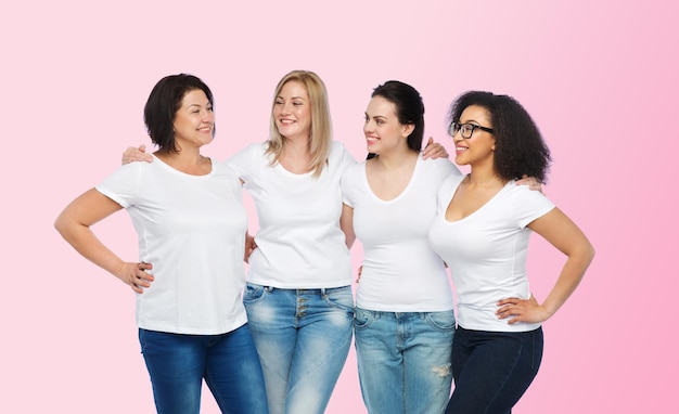 friendship, diverse, body positive, communication and people concept - group of happy different size women in white t-shirts hugging and talking over pink background