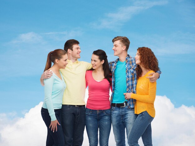 friendship, dream, future and people concept - group of smiling teenagers over blue sky with white cloud background