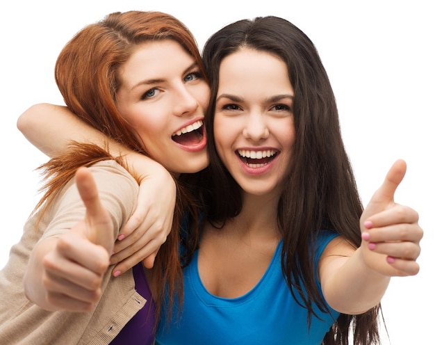 friendship and happy people concept - two smiling girls showing thumbs up