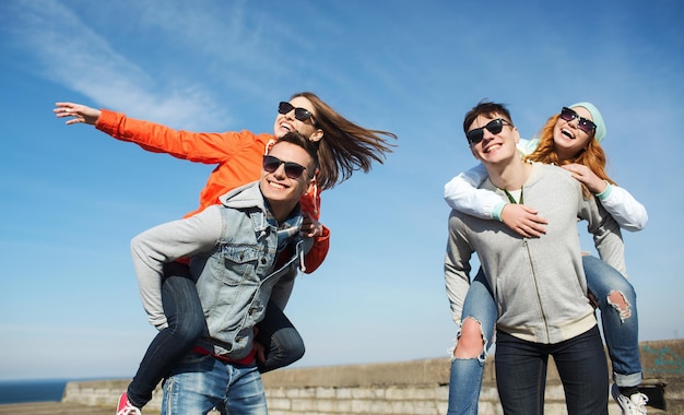 friendship, leisure and people concept - group of happy teenage friends in sunglasses having fun outdoors