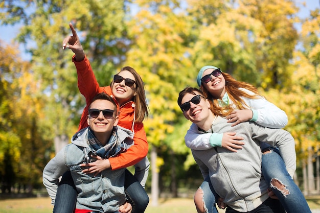 friendship, leisure, season and people concept - group of happy teenage friends in sunglasses having fun over autumn park background