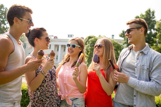 friendship, leisure, sweets, summer and people concept - group of smiling friends with ice cream outdoors