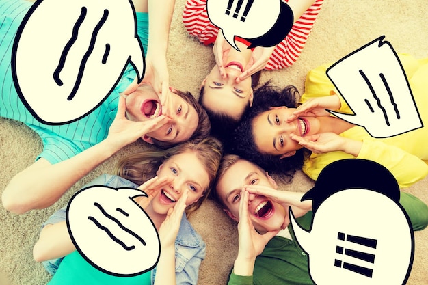 friendship, lifestyle and happiness concept - group of young smiling people lying on floor in circle screaming and shouting