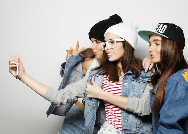 Friendship people and technology concept three happy teenage girls with smartphone taking selfie