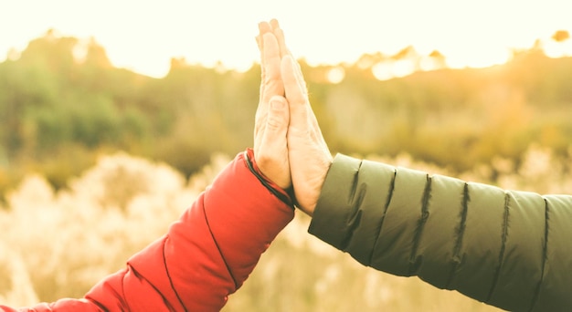 Friendship and relationship concept with hands clasped man and woman in outdoor with nature in background Unrecognizable people Team and help couple Giving five Love and friends leisure activity