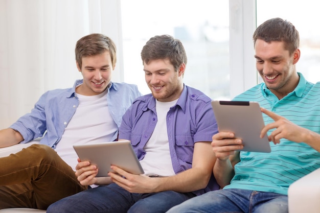 friendship, technology and home concept - smiling male friends with tablet pc computers at home