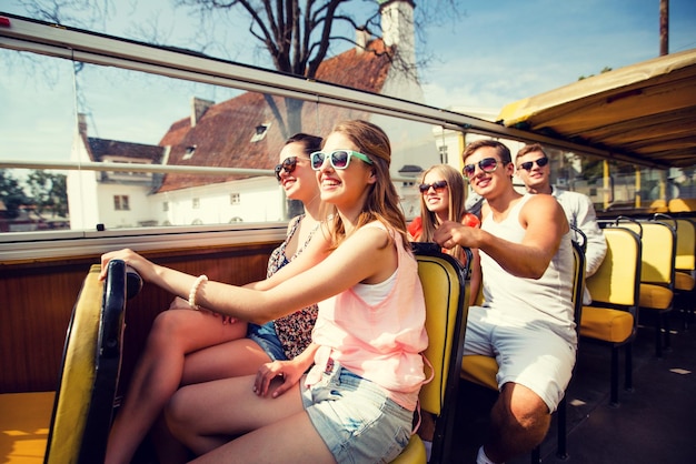 Photo friendship, travel, vacation, summer and people concept - group of smiling friends traveling by tour bus