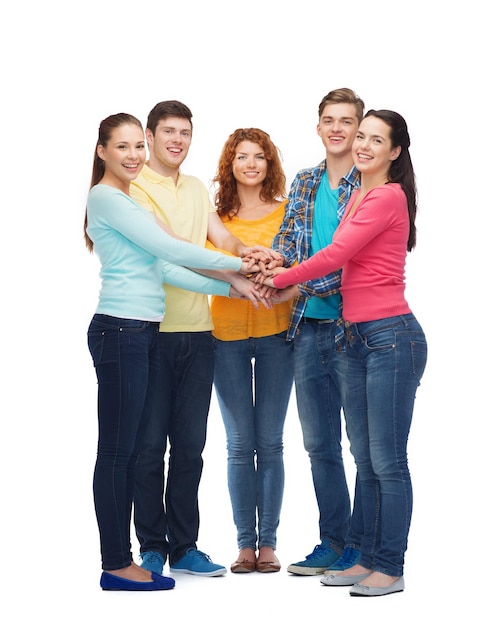 friendship, youth, gesture and people - group of smiling teenagers with hands on top of each other