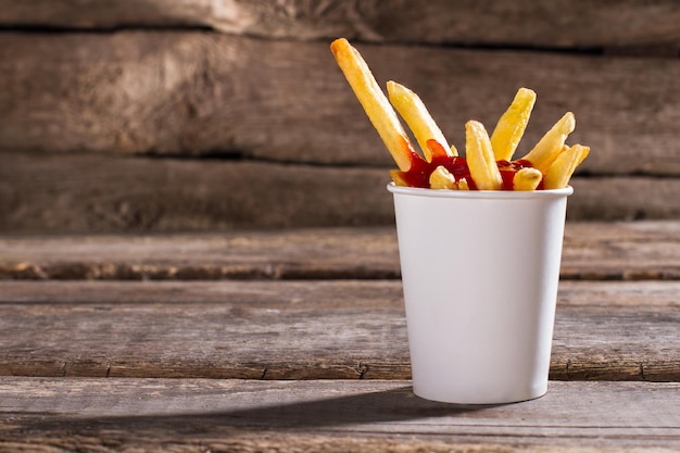 Photo fries with sauce in cup french fries with tomato ketchup aged table with tasty snack popular fast food dish