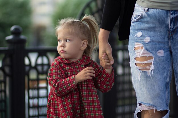 Frightened face of the caucasian child of two years old holding mother hand