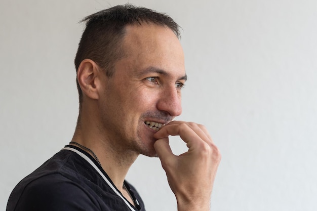 Frightened man feeling scared and biting his nails on a light background.