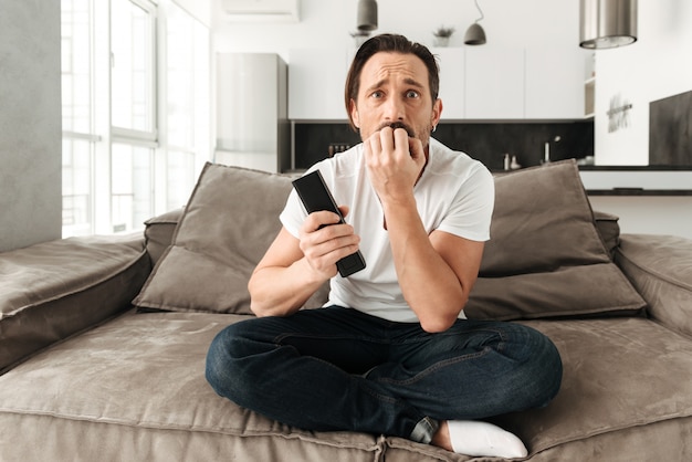 Frightened mature man sitting on a sofa