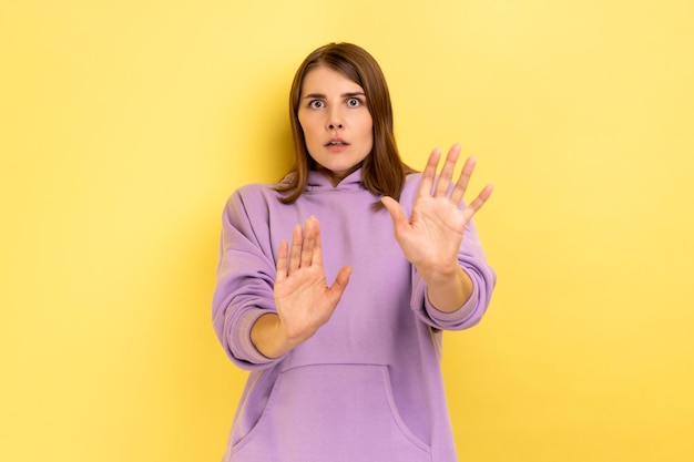 Frightened shocked woman raising hands in fear looking horrified and panicking hiding from phobia