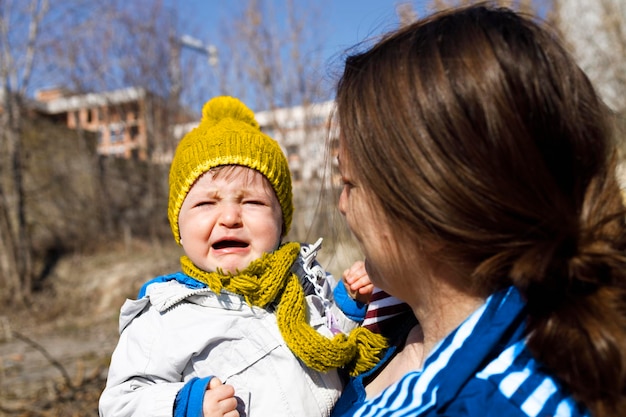 A frightened small kid crying in her mothers arms