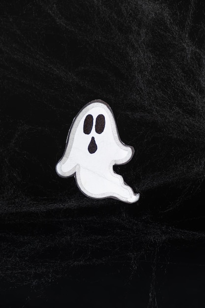 A frightening white ghost flies on a black background with a web a Halloween postcard