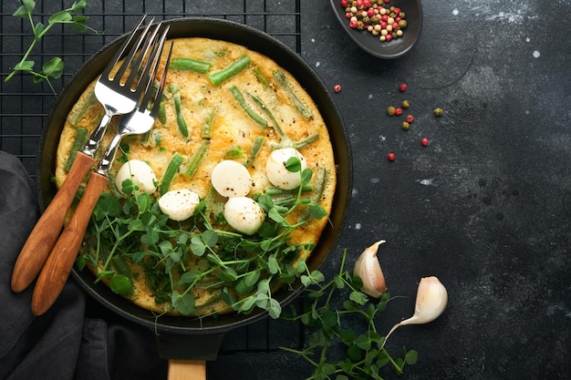 Frittata Omelet with spinach and green beans healthy food in black frying pan on dark old rustic background Healthy breakfast delicious Top view flat lay Copy space