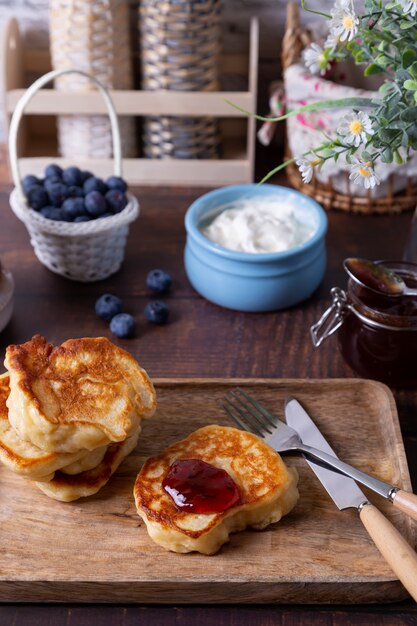 Fritters with sour cream, jam and blueberries. The traditional Russian dish. Close-up.