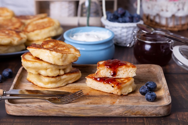 Fritters with sour cream, jam and blueberries. The traditional Russian dish. Close-up.