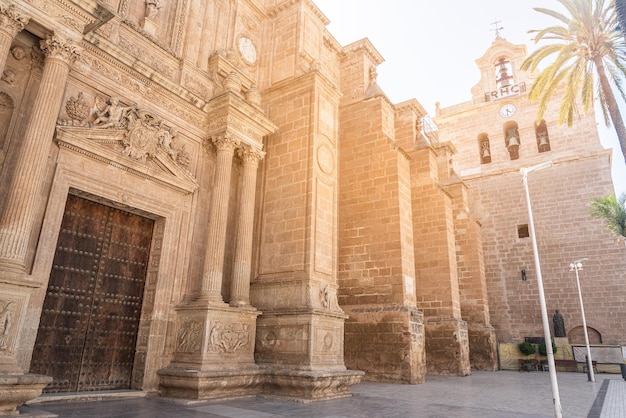 From below of ancient stone Almeria Cathedral of Incarnation in Spain with ornamental bas relief above doorway and columns placed symmetrically from entrance door in sunny day