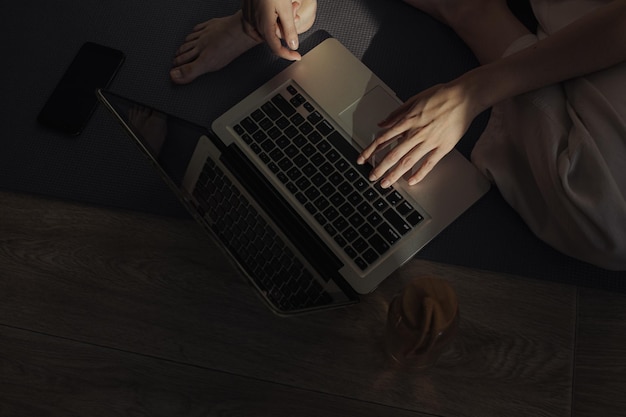 From above of crop barefoot woman using laptop during online fitness training at home