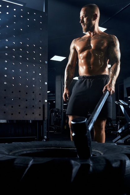 From above view of muscular caucasian man carrying big sledgehammer in hand.