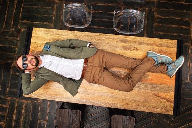 Photo from above view of young handsome man lying on wooden table