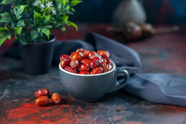 Front close view of fresh raw silverberry fruits inside and outside of a gray cup and flower pot on mix colors background with free space