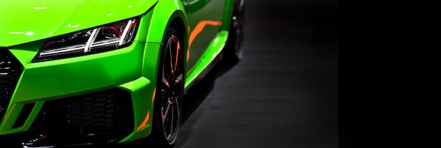 Front headlights of green modern sport car on black background free space on right side for text