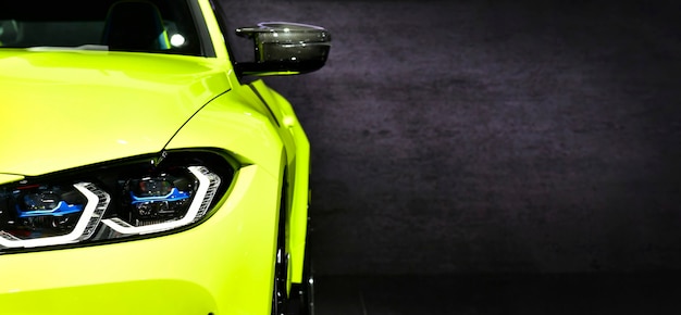 Front headlights of green modern sport car on black background