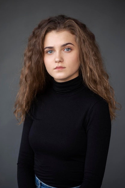 Front image portrait of a girl with curly hair on a grey background