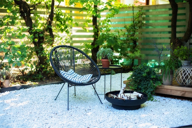 Front loft veranda of house with two black armchairs, coffee table and fireplace bowl in garden