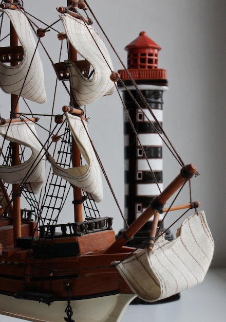 Front Part And Bowsprit Of Toy Masted Ship In Front Of Miniature Beacon Tower