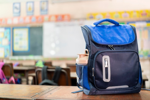 Front of stylish school bag backpack supplies on a table desk at the green chalkboard Back to school education concept