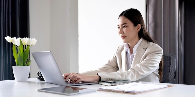 Front view of a beautiful Asian businesswoman working on a tablet coffee cup placed on the office table