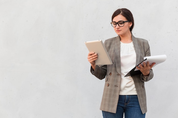 Front view of businesswoman outdoors with tablet and notepad