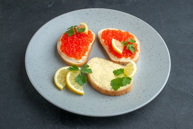 front view caviar sandwiches with lemon inside blue plate on dark surface